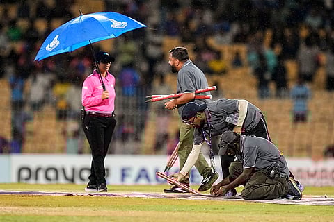 Ground staff at the pitch as rain stops play
